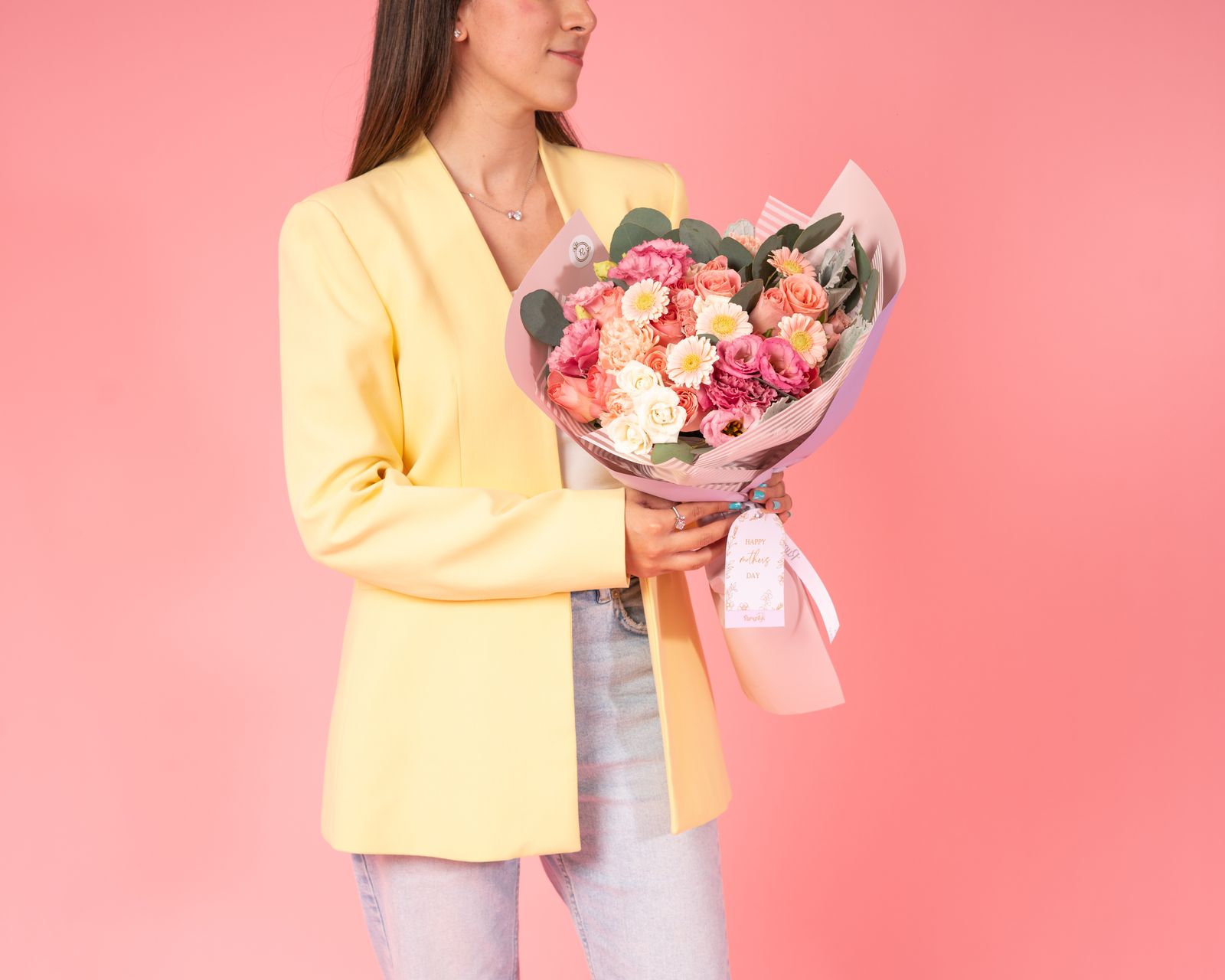 Femeie elegantă cu buchet floral vibrant pe fundal roz